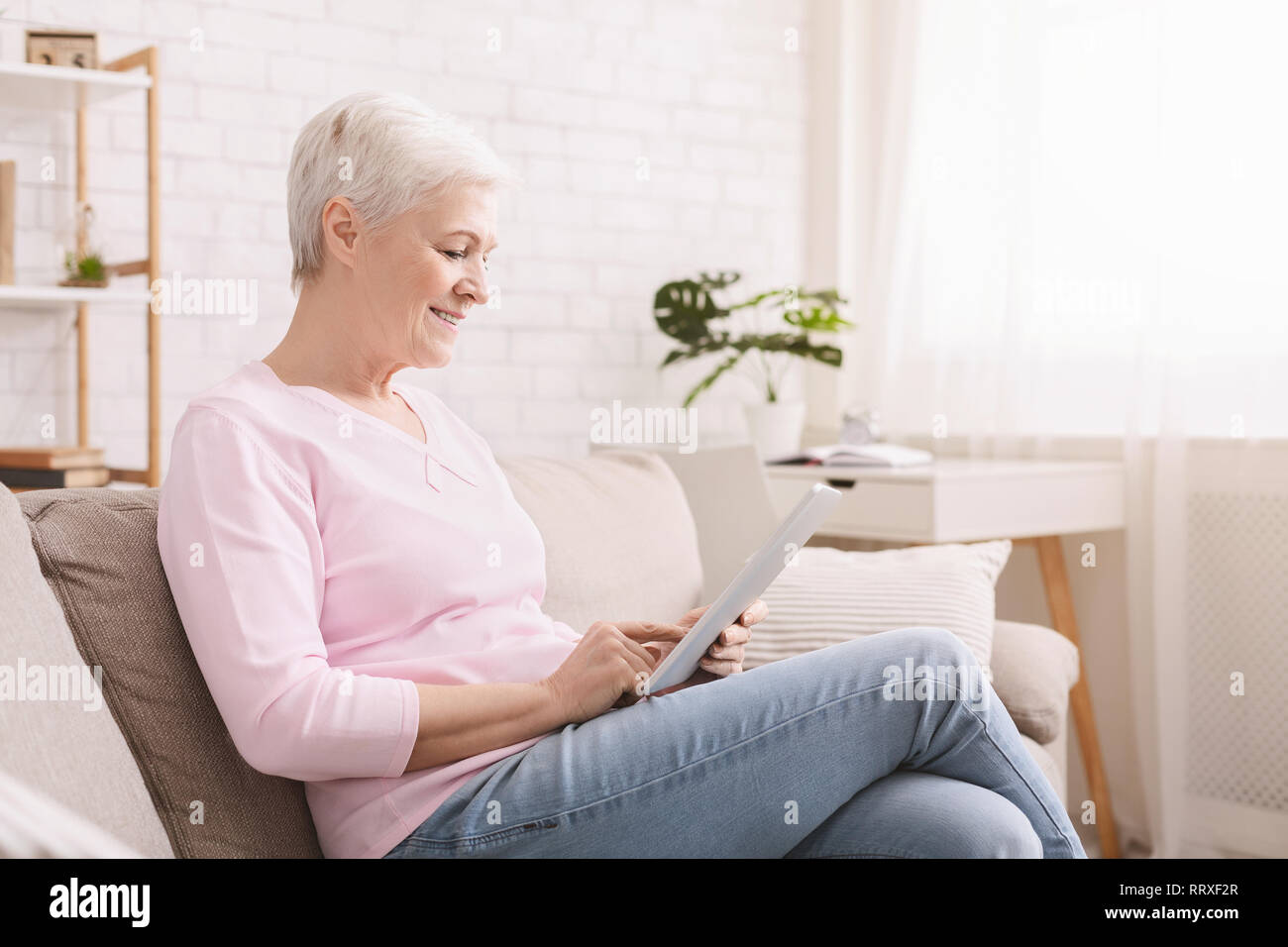 Smiling beautiful senior woman using digital tablet Stock Photo