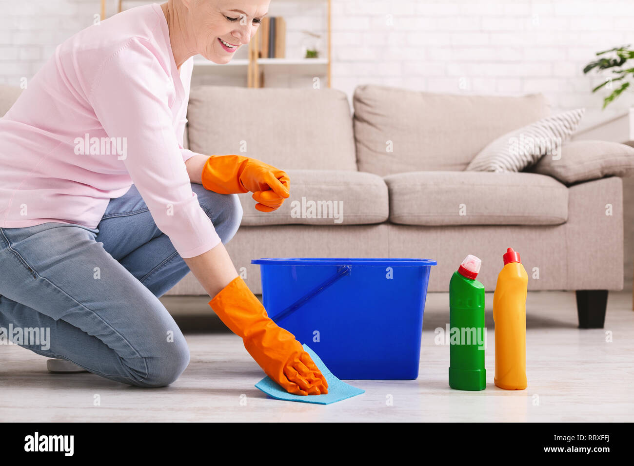 Smiling mature housewife cleaning floor at home Stock Photo