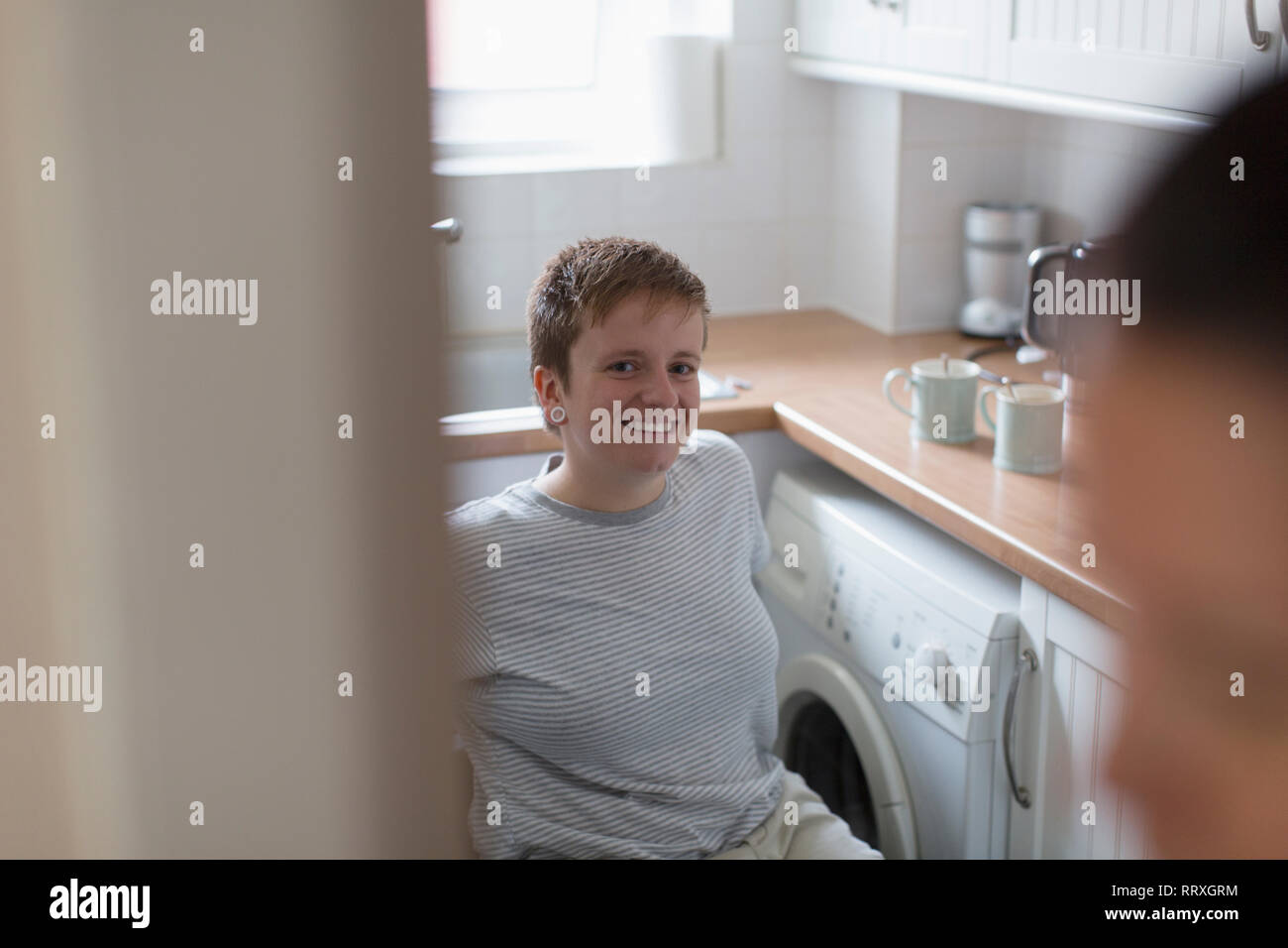 Portrait confident young woman in wheelchair in apartment kitchen Stock Photo