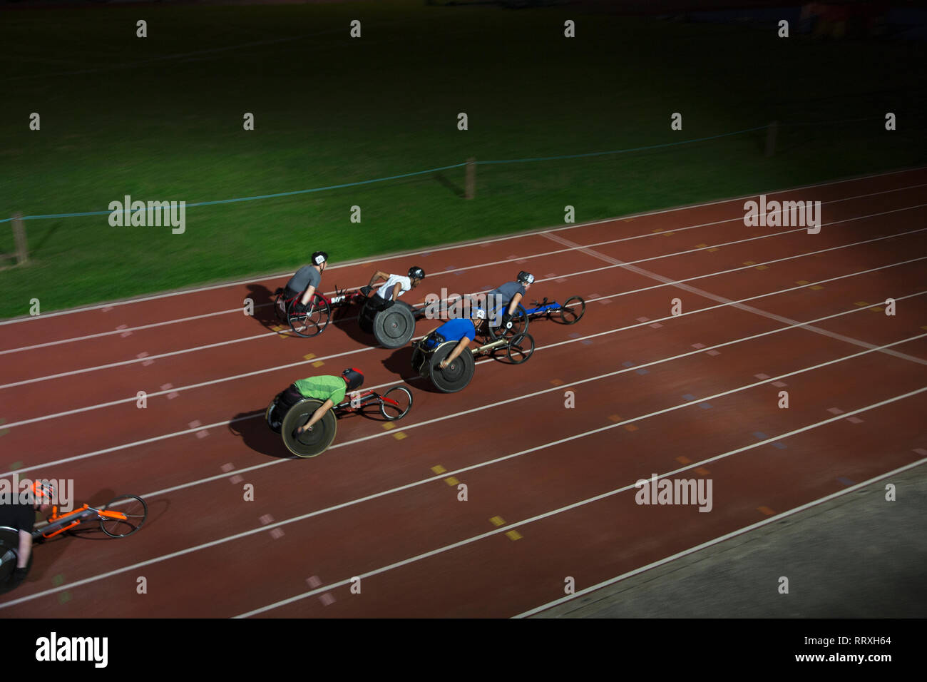 Paraplegic athletes speeding along sports track in wheelchair race at