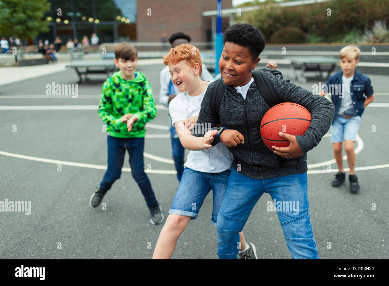 Tween boys playing basketball in schoolyard Stock Photo