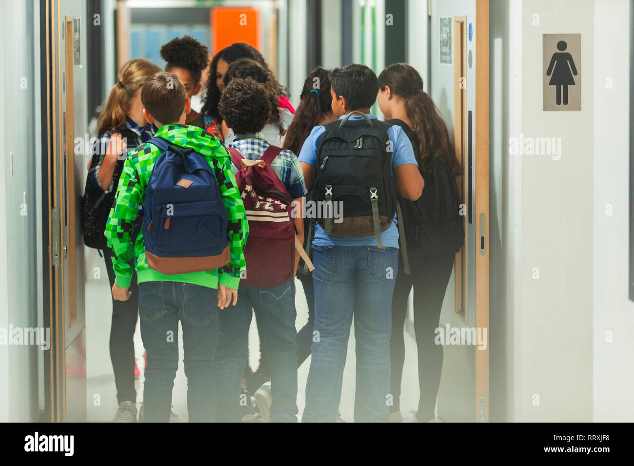 Junior high students with backpacks walking in school corridor Stock Photo