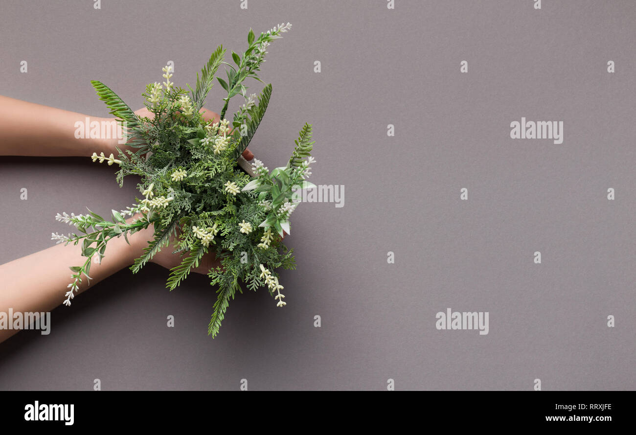 Woman holding artificial houseplant with white flowers Stock Photo
