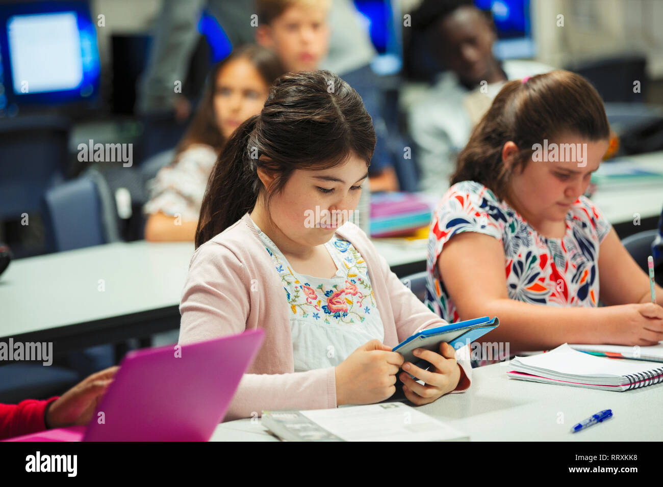 Focused junior high school girl student using digital tablet in classroom Stock Photo