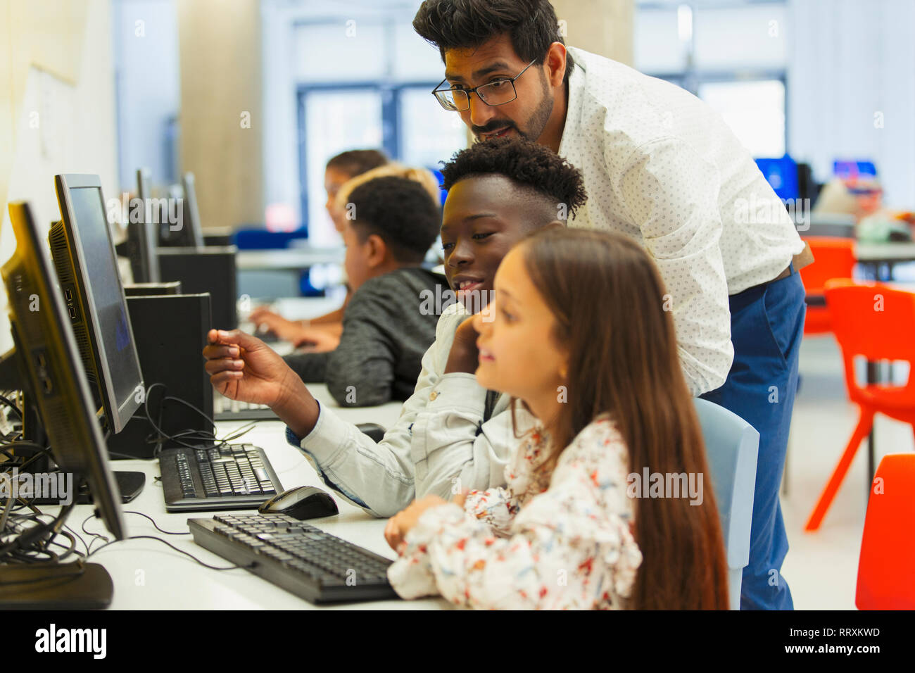 Teacher helping junior high students using computer in computer lab Stock Photo