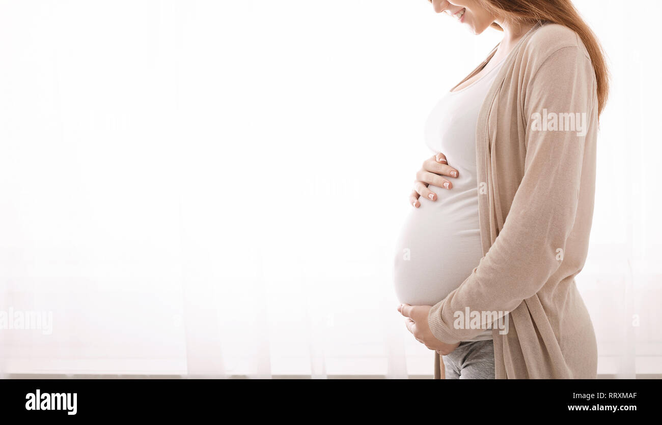 Beautiful pregnant woman hugging her tummy at home Stock Photo - Alamy