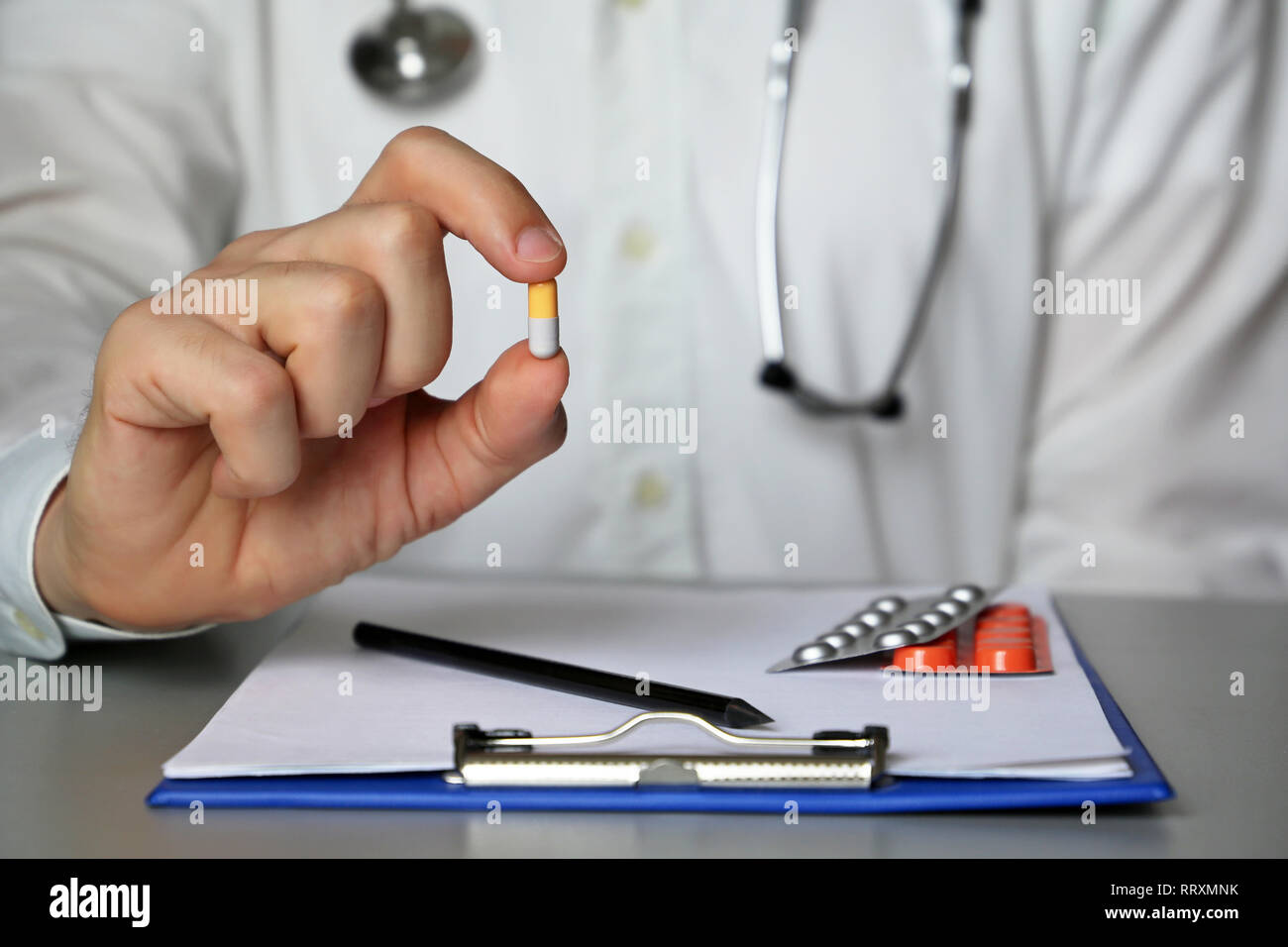 Doctor with pill sitting at the table, giving medication in capsules. Concept of health care, medical appointment, prescription, pharmacy Stock Photo