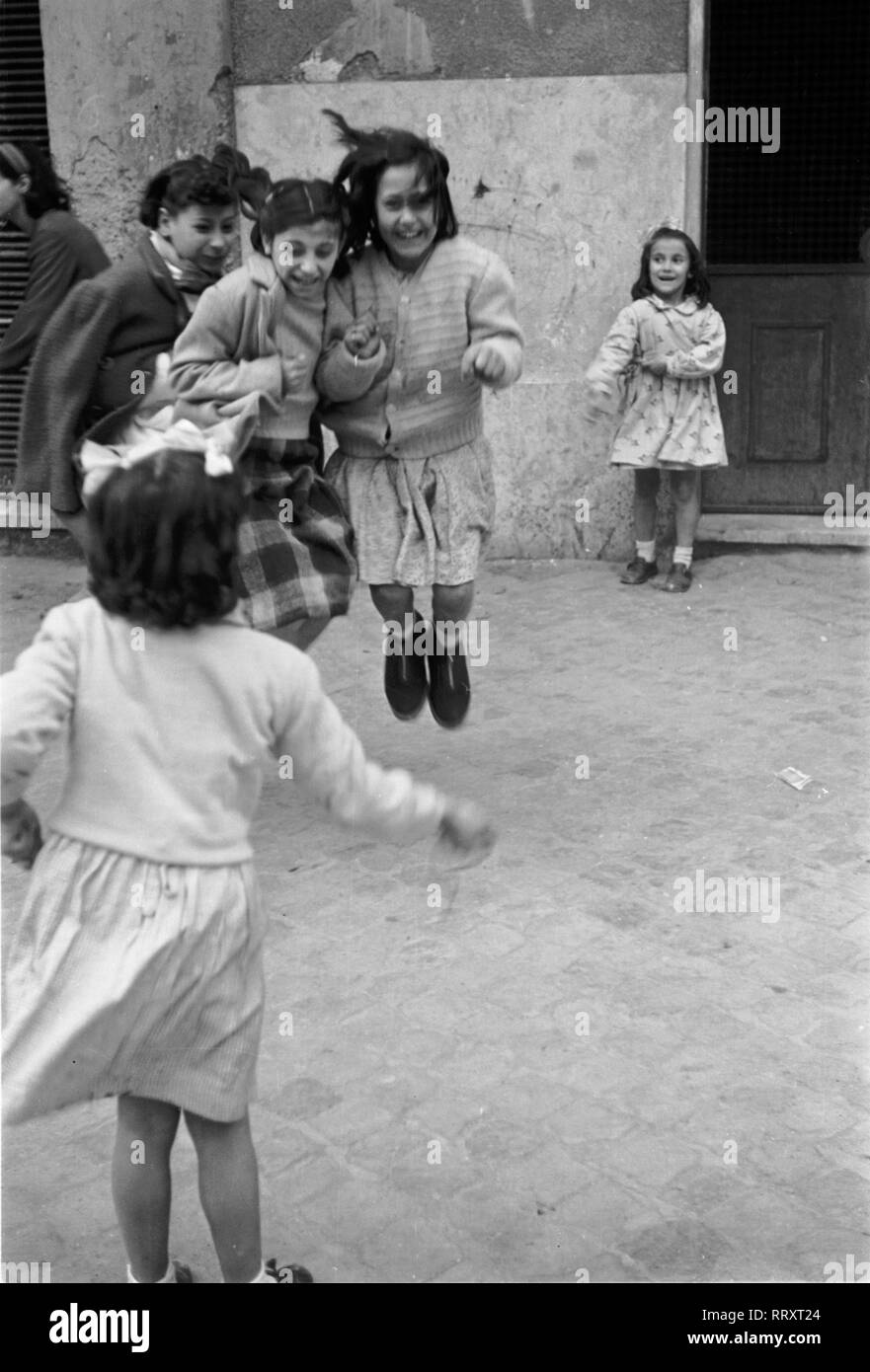 Italien - Mädchen beim Seilspringen in einem Hof in Rom, Italien 1950er Jahre. Girls doing some rope skipping at a backyard in Rome, Italy 1950s. Stock Photo