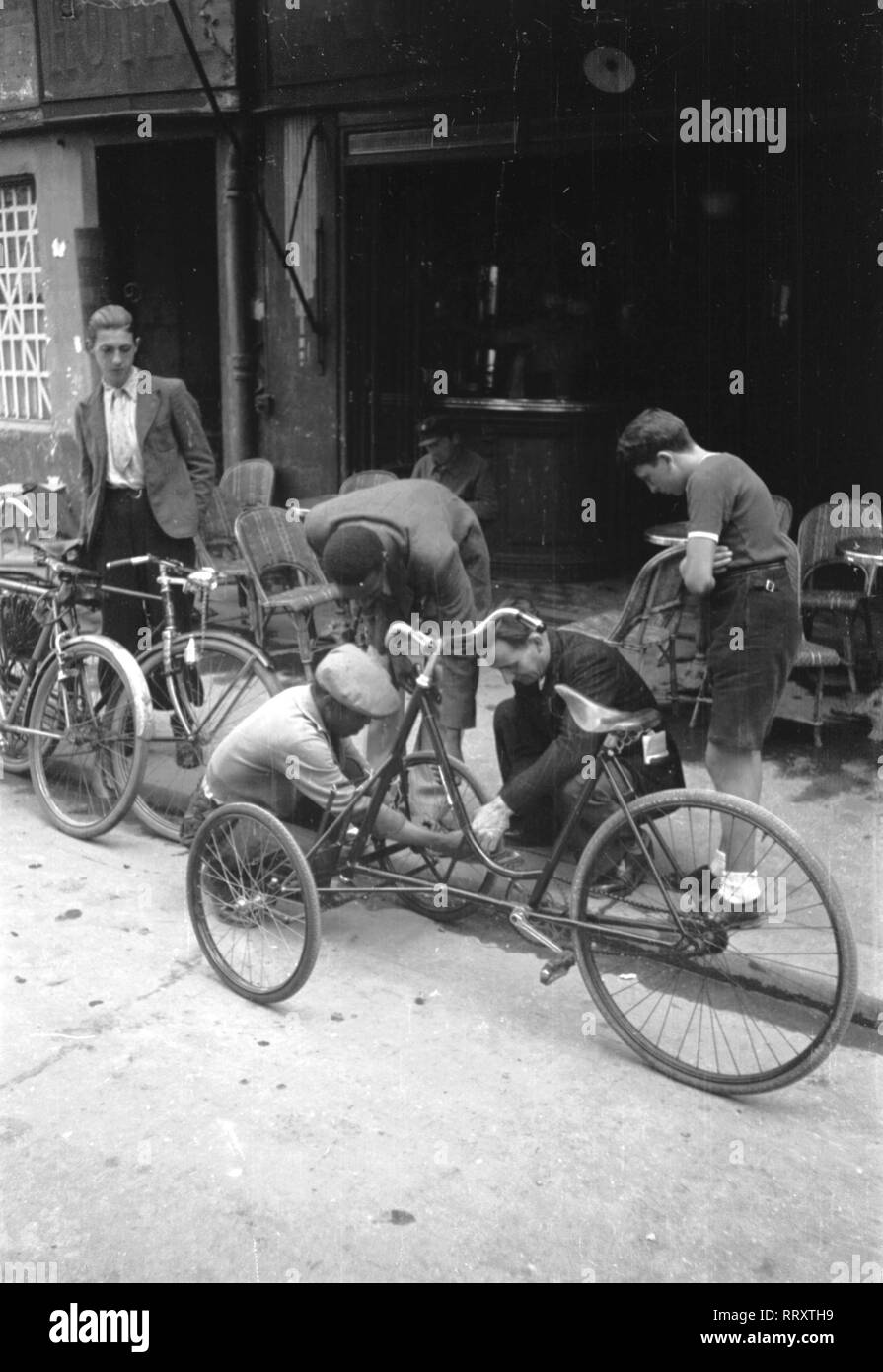 Men - Männer beim Reparieren eines Fahrrads, 1950er Jahre. Men repairing a trcycle, ca. 1950s. Stock Photo