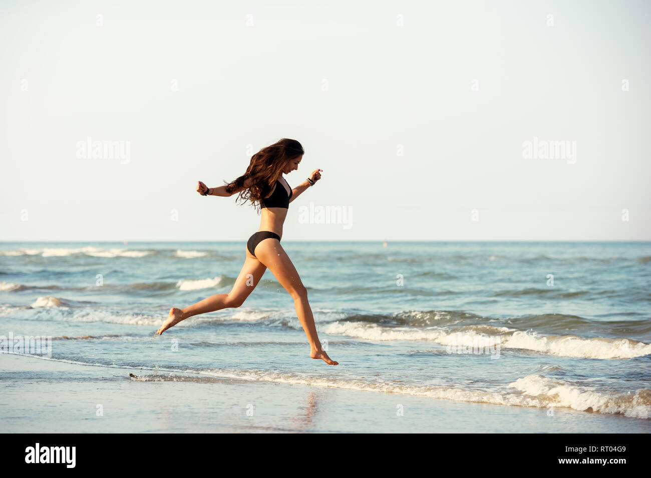 Happy beautiful slim lady runs at sea beach Stock Photo