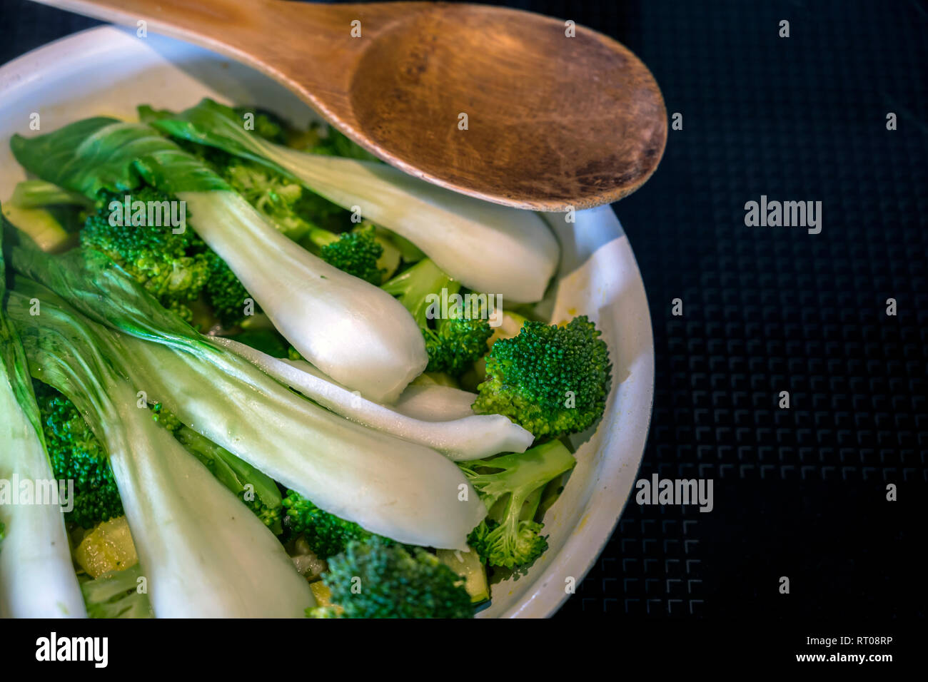 Long-leafed Cabbage with onion and broccoli stew in frying pan on an electric stove - dietary low-calorie natural organic dish that is good for your h Stock Photo
