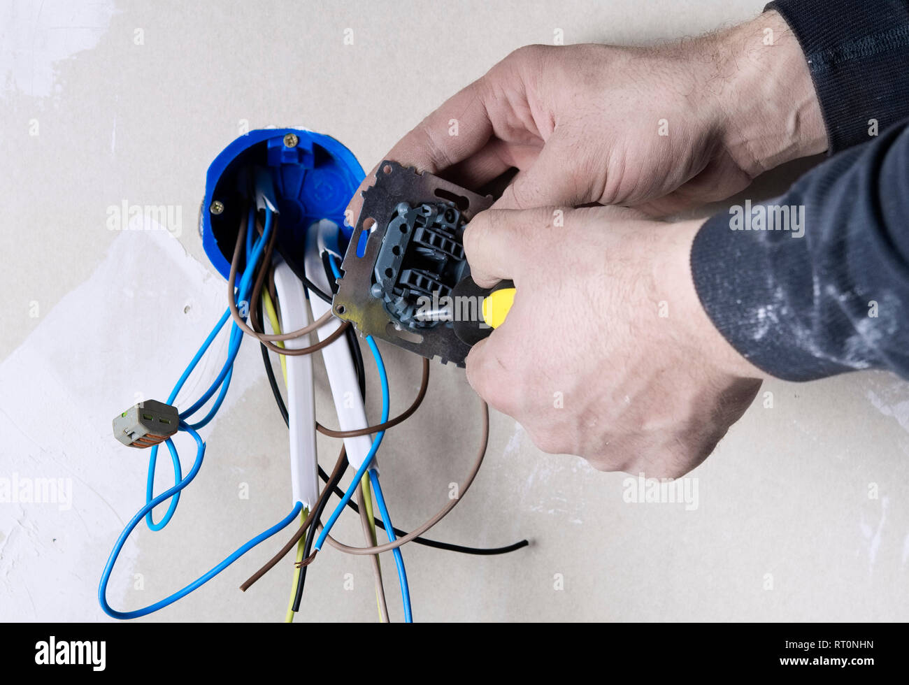 The electrician technician at work sticks the cable between the clamps