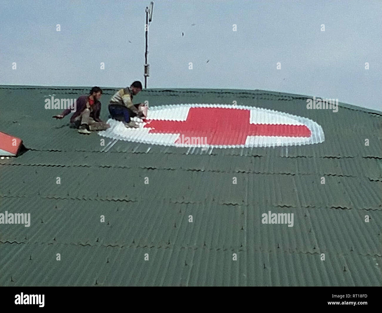 Srinagar, Kashmir. 27th Feb 2019.A Kashmiri worker paints the red and white medical emblem of cross on the roof of SMHS hospital as tensions escalate between India and Pakistan Credit: sofi suhail/Alamy Live News Stock Photo
