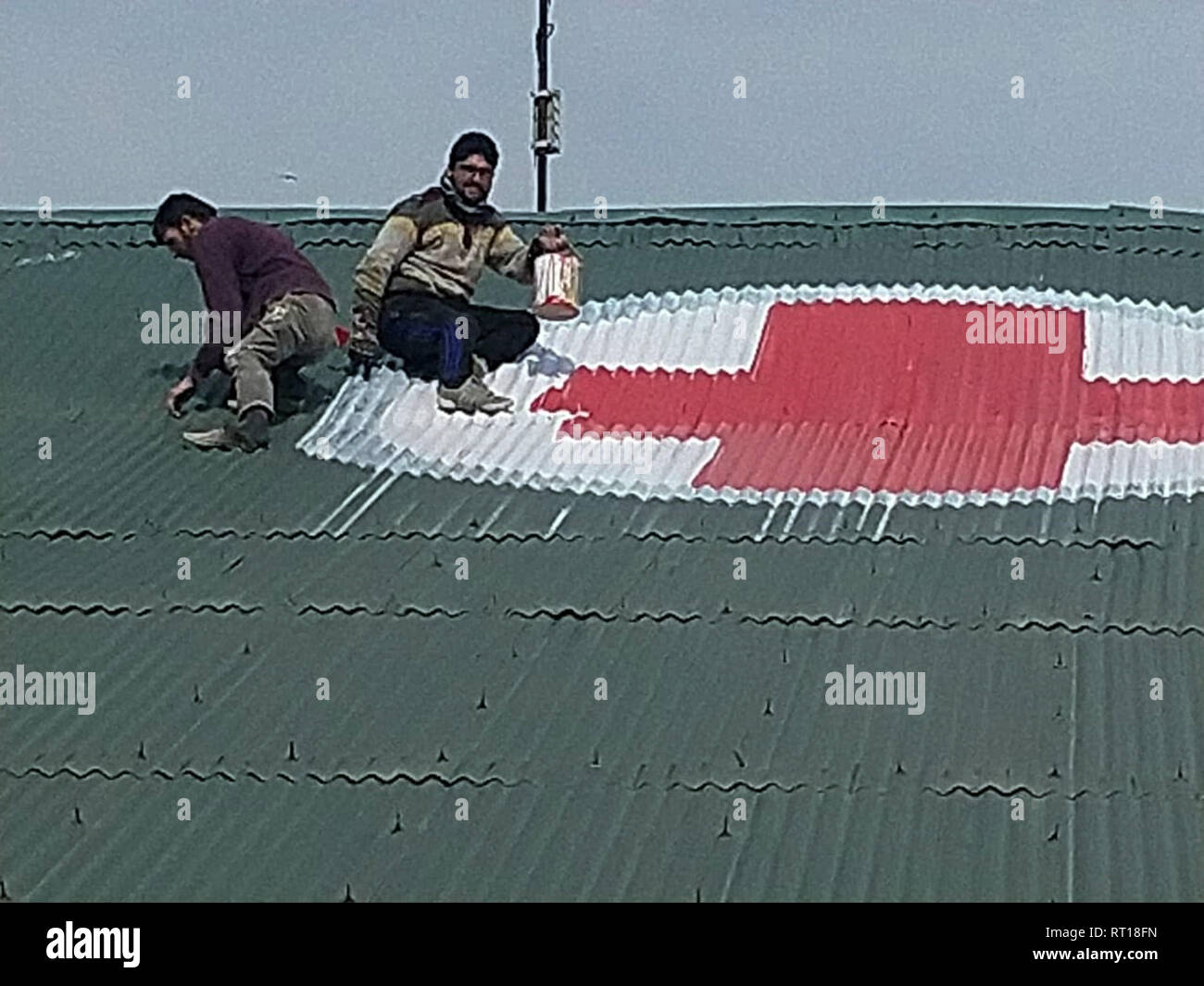 Srinagar, Kashmir. 27th Feb 2019.A Kashmiri worker paints the red and white medical emblem of cross on the roof of SMHS hospital as tensions escalate between India and Pakistan Credit: sofi suhail/Alamy Live News Stock Photo