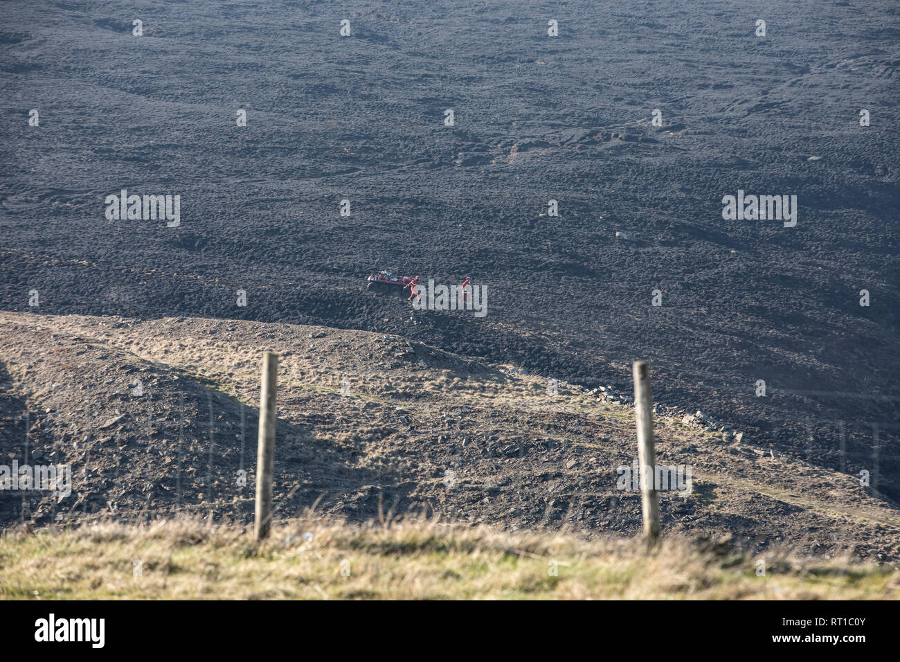 Marsden, UK. 27th Feb, 2019. Scorched moorland was still smouldering this afternoon following the dramatic fire overnight at Marsden Moor, near Saddleworth Moor. Firemen were using a special buggy, and breathing equipment, to survey areas of ground still smouldering. Credit: James Copeland/Alamy Live News Stock Photo