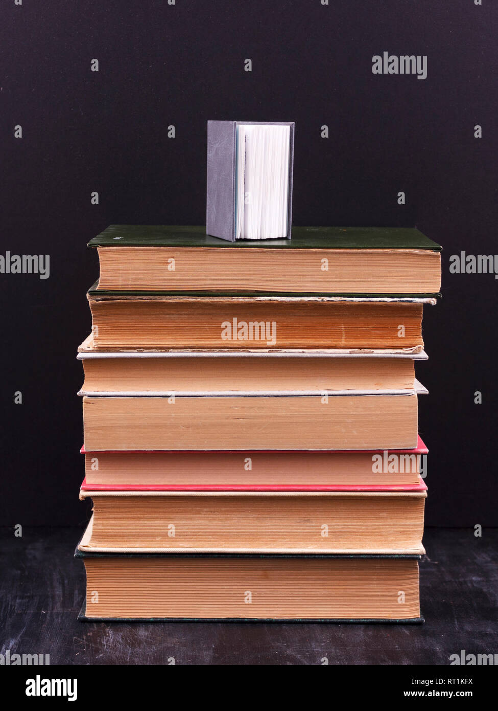 Stack of books on black background with small book on top Stock Photo ...