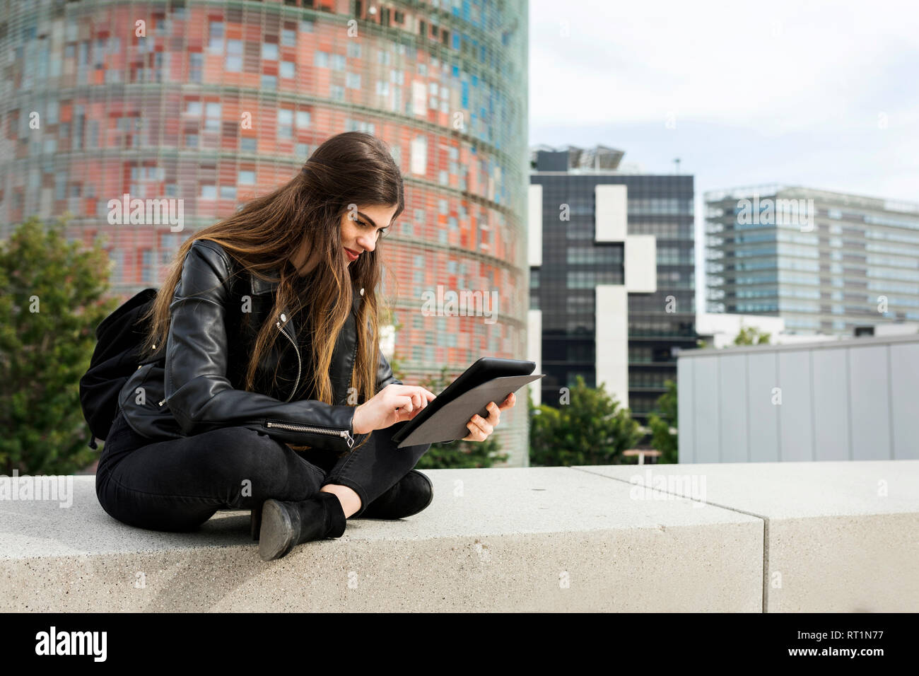 Spain Barcelona, young woman sitting in the city using tablet Stock Photo
