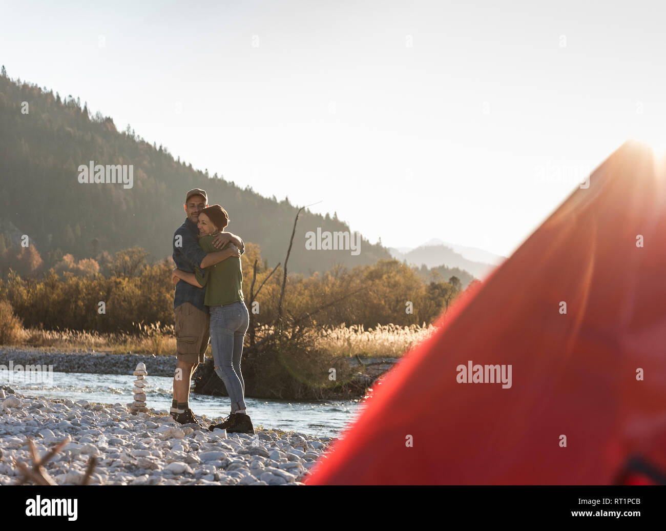 Mature couple camping at riverside in the evening light Stock Photo