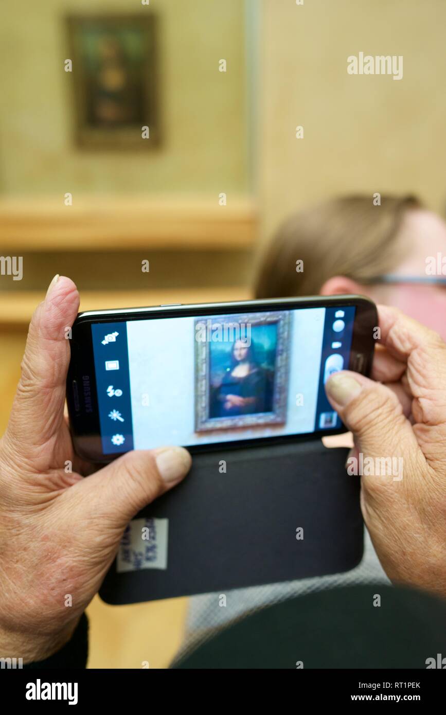PARIS, FRANCE - APRIL 3, 2015: Tourists photographing the famous picture of Gioconda in Louvre Museum. Stock Photo