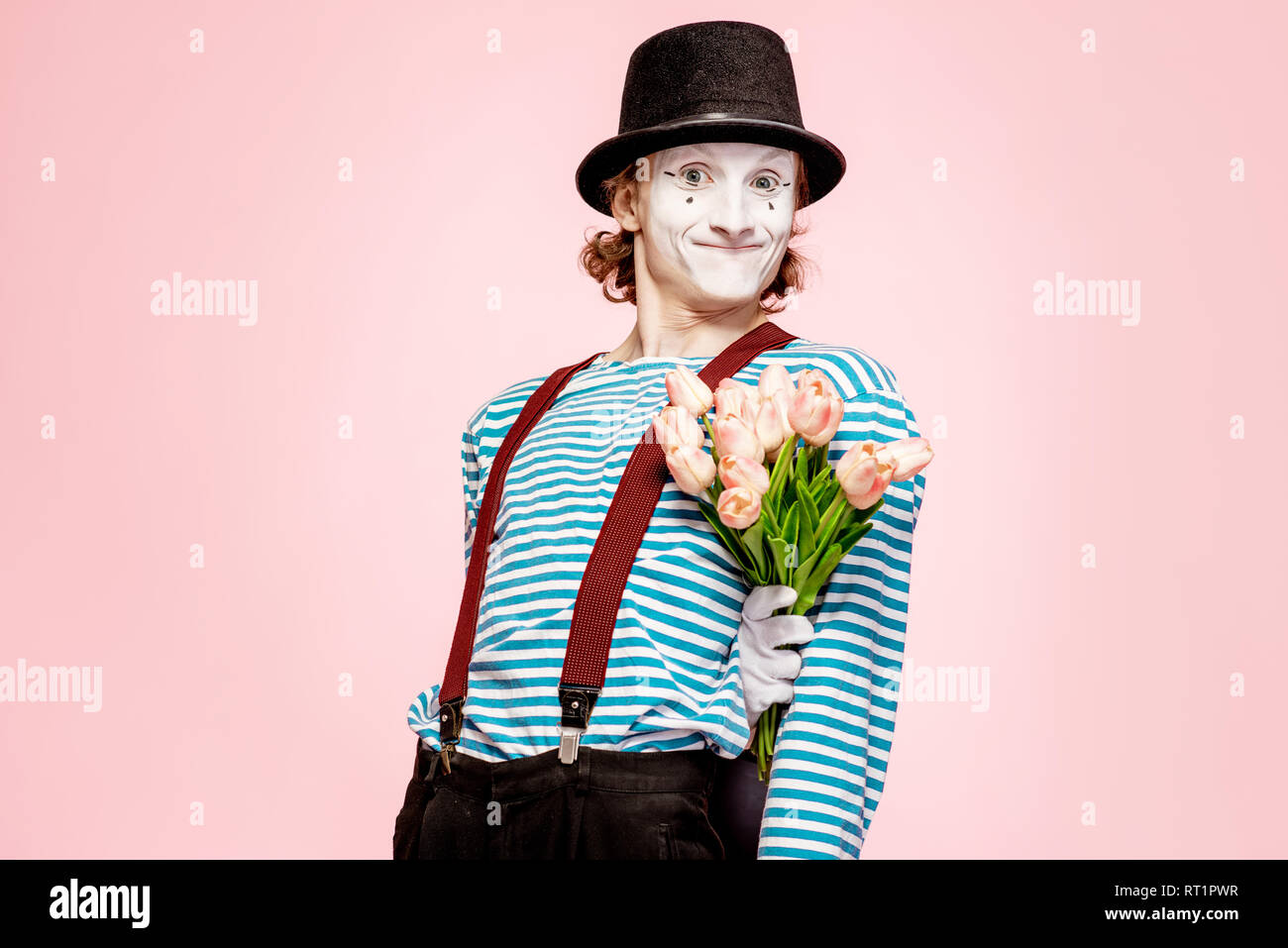 Emotional pantomime posing with tulip bouquet on the pink background indoors. Valentine's Day and love concept Stock Photo