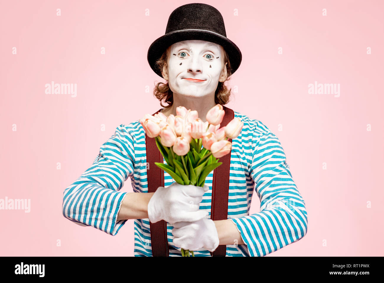 Emotional pantomime posing with tulip bouquet on the pink background indoors. Valentine's Day and love concept Stock Photo