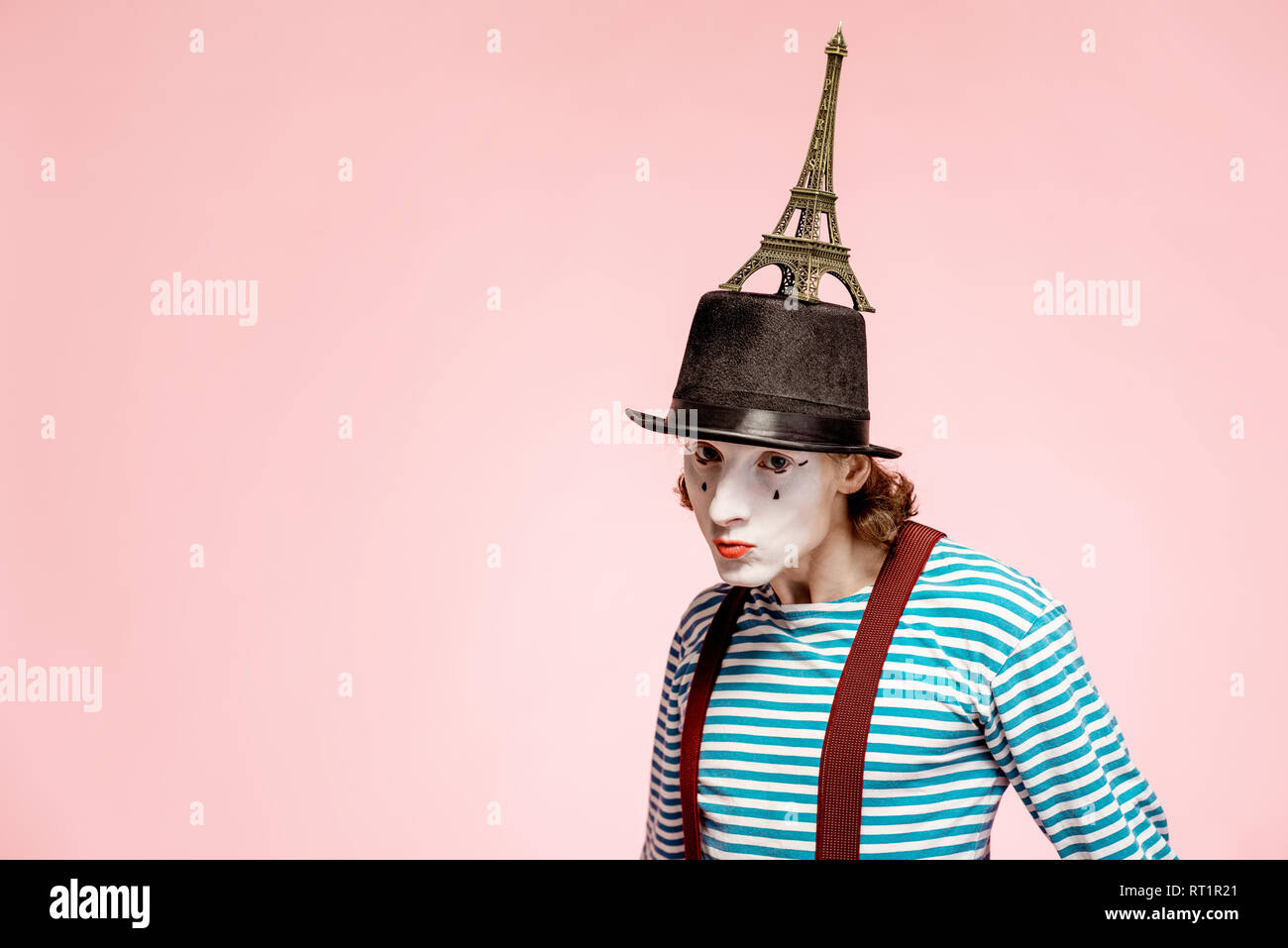 Pantomime with white facial makeup posing with Eiffel tower on the pink background. French mime concept Stock Photo