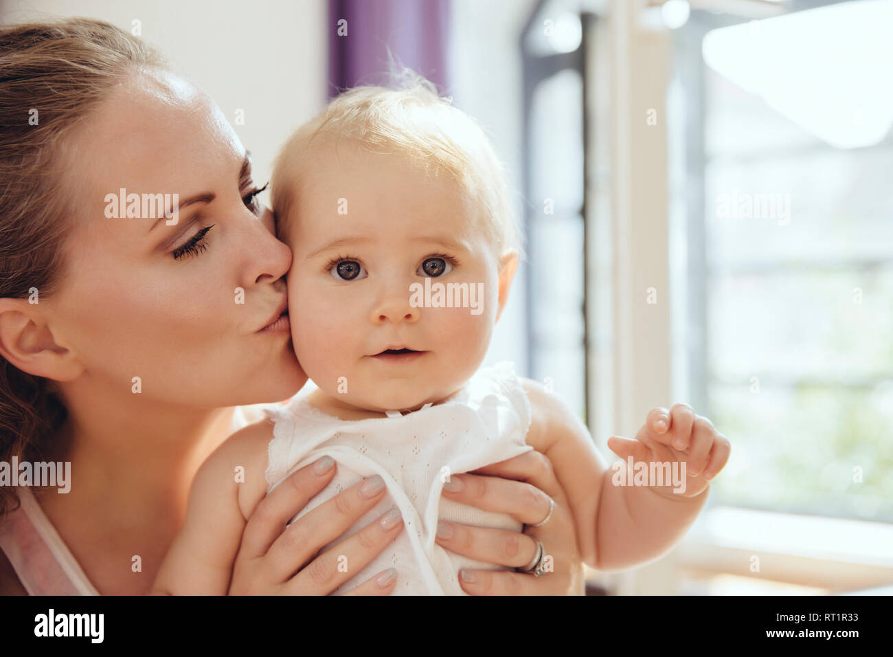 Mother kissing her baby on cheek Stock Photo