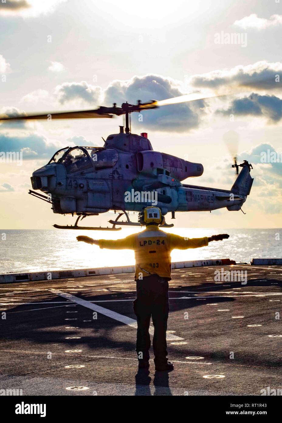 190221-N-HG389-0080 MEDITERRANEAN SEA (Feb. 21, 2019) Aviation Boatswain’s Mate (Handling) 3rd Class Kenneth Smith signals to an AH-1W Super Cobra helicopter assigned to the “Black Knights” of Marine Medium Tiltrotor Squadron (VMM) 264 (Reinforced) as it lands on the flight deck of the San Antonio-class amphibious transport dock ship USS Arlington (LPD 24), Feb. 21, 2019. Arlington is on a scheduled deployment as part of the Kearsarge Amphibious Ready Group in support of maritime security operations, crisis response and theater security cooperation, while also providing a forward naval presenc Stock Photo