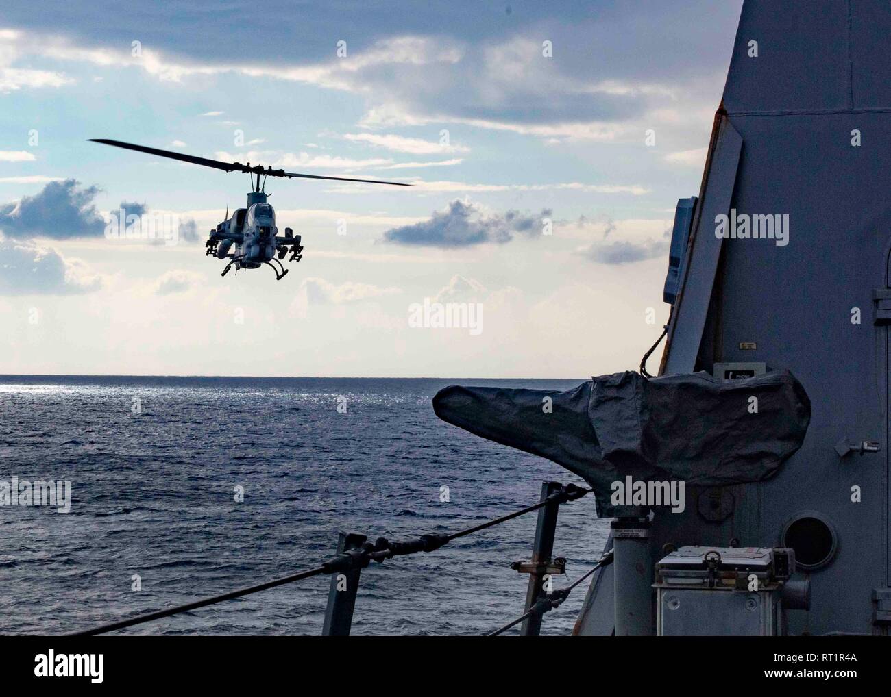190221-N-HG389-0051 MEDITERRANEAN SEA (Feb. 21, 2019) An AH-1W Super Cobra helicopter assigned to the “Black Knights” of Marine Medium Tiltrotor Squadron (VMM) 264 (Reinforced) flies by the San Antonio-class amphibious transport dock ship USS Arlington (LPD 24), Feb. 21, 2019. Arlington is on a scheduled deployment as part of the Kearsarge Amphibious Ready Group in support of maritime security operations, crisis response and theater security cooperation, while also providing a forward naval presence. (U.S. Navy photo by Mass Communication Specialist 2nd Class Brandon Parker/Released) Stock Photo