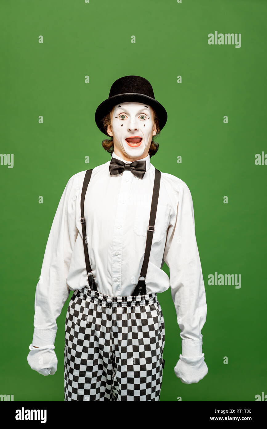 Portrait of an actor as a pantomime with white facial makeup posing with expressive emotions isolated on the green background Stock Photo
