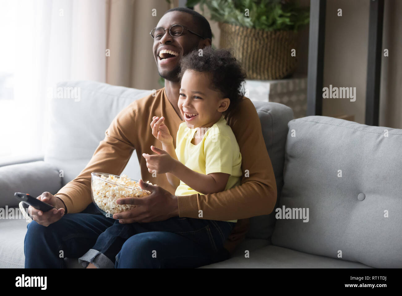 Happy african dad and kid son laughing watching funny comedy Stock
