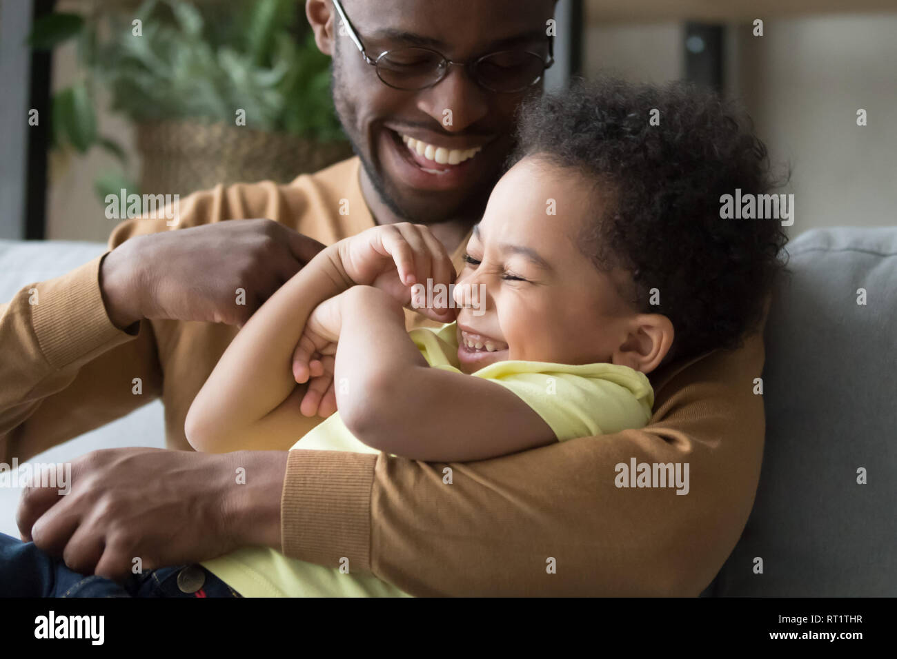 Affectionate loving african dad holding tickling child toddler son Stock Photo
