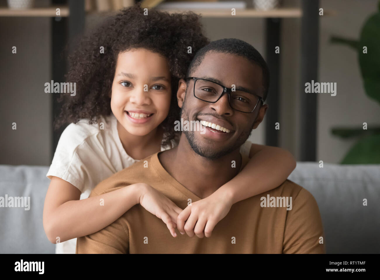 Happy mixed-race preschool girl embracing black father looking at camera Stock Photo