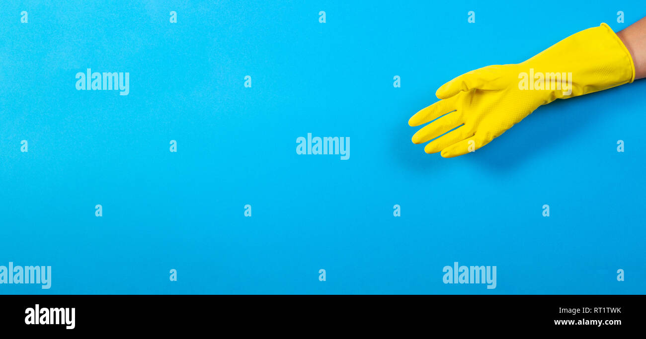 One woman hand in yellow rubber glove over blue background Stock Photo