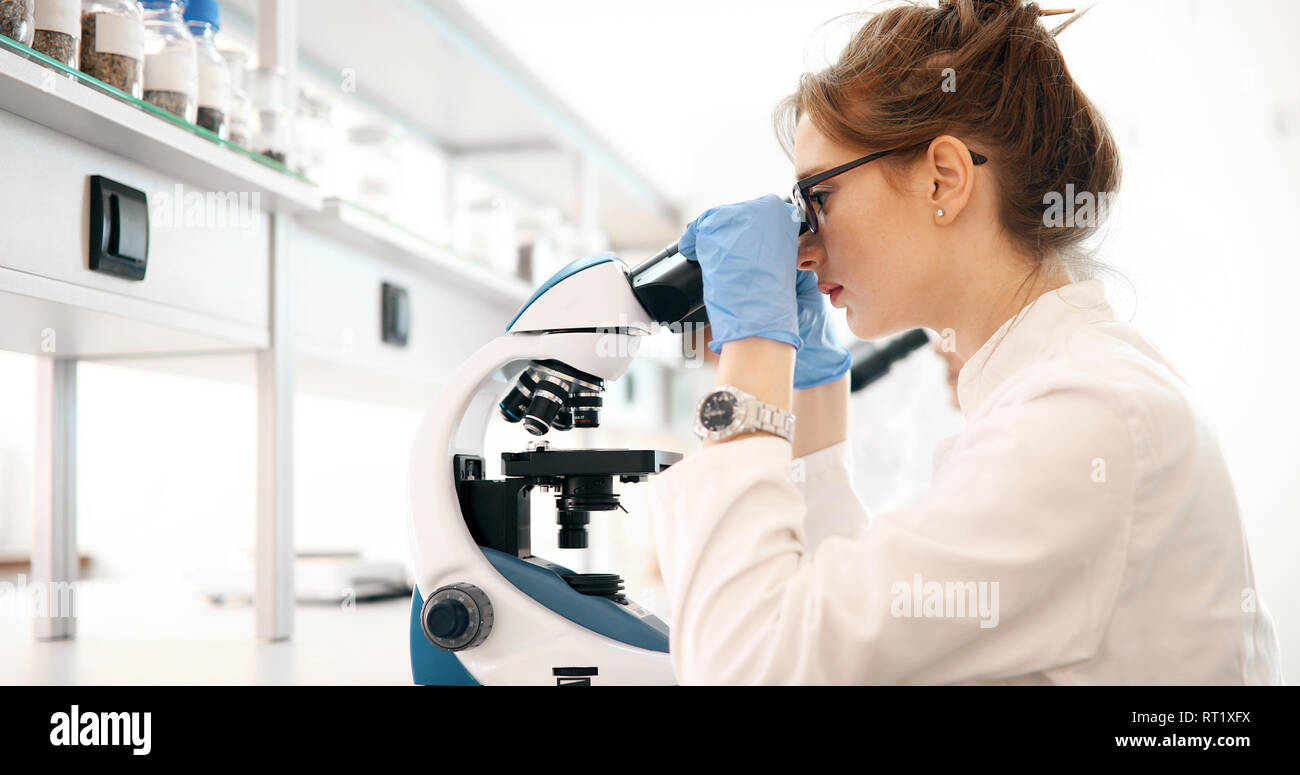 Young scientist looking through microscope in laboratory Stock Photo ...