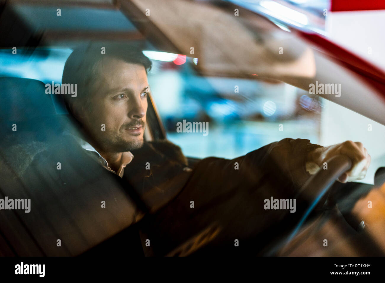 Businessman driving in his car at night Stock Photo