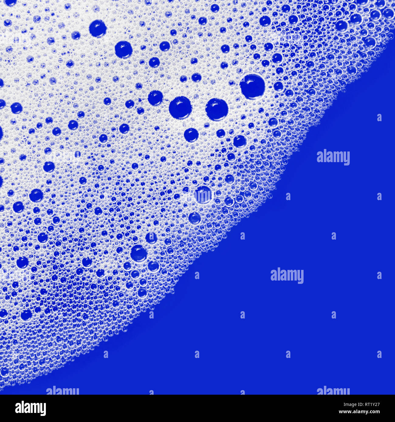 Soap sud. Foam with bubbles on blue background. Detergent in water