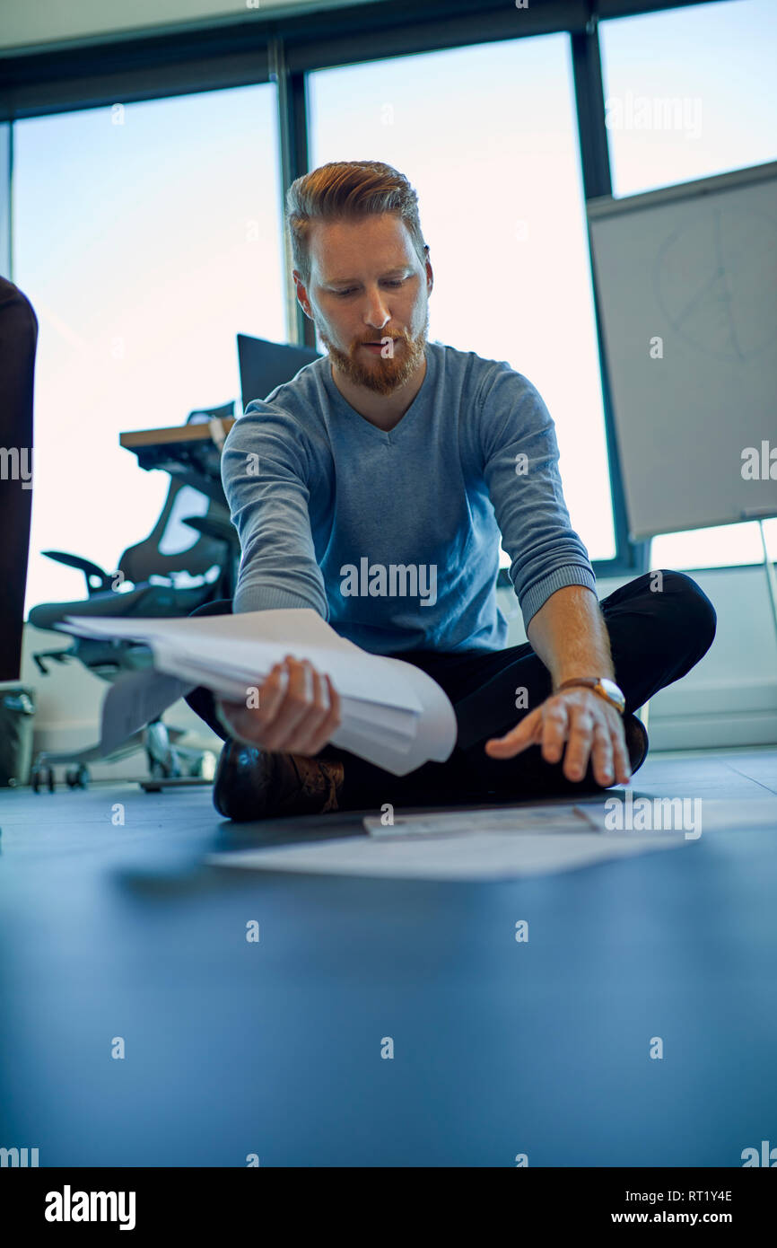 Businessman organising papers on the floor in office Stock Photo