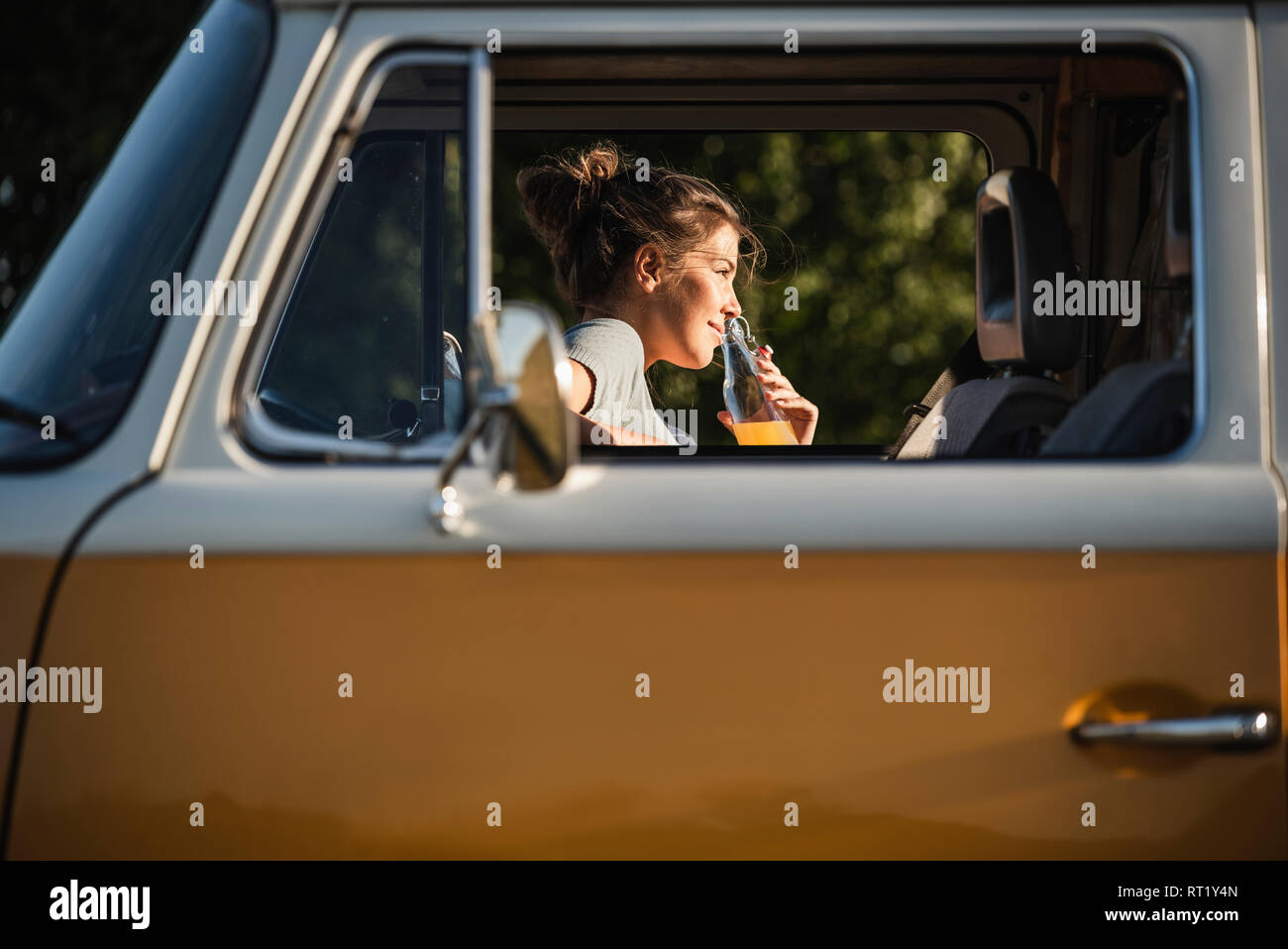Pretty woman on a road trip with her camper, taking a break, drinking juice Stock Photo
