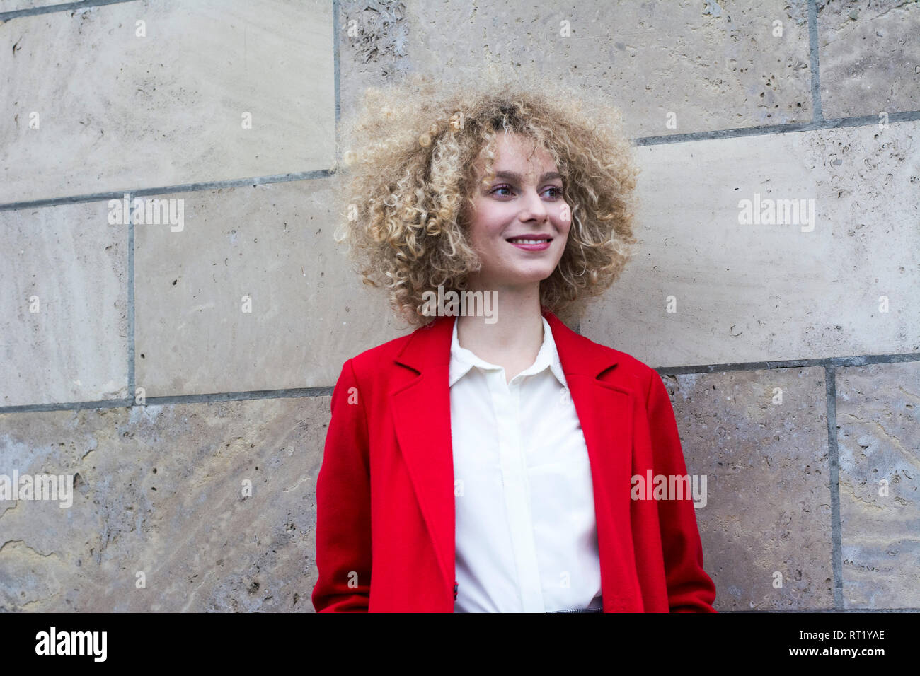 Portrait of smiling blond woman with ringlets wearing red suit coat Stock Photo