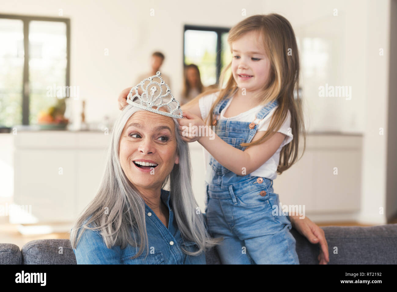 Granddaughter putting crown on grandmothes head Stock Photo