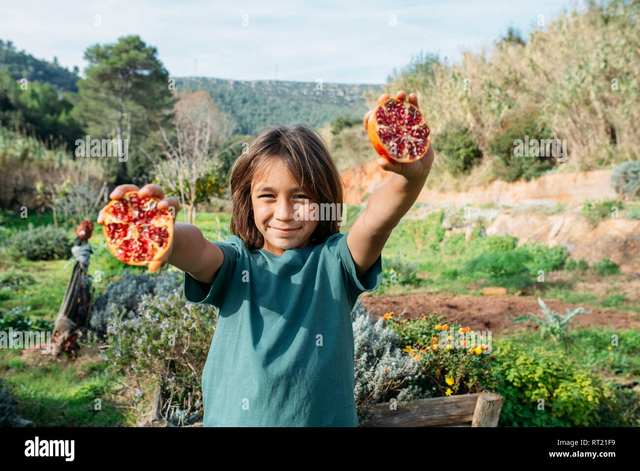 Boy holding halved pomegranate in an orchard Stock Photo