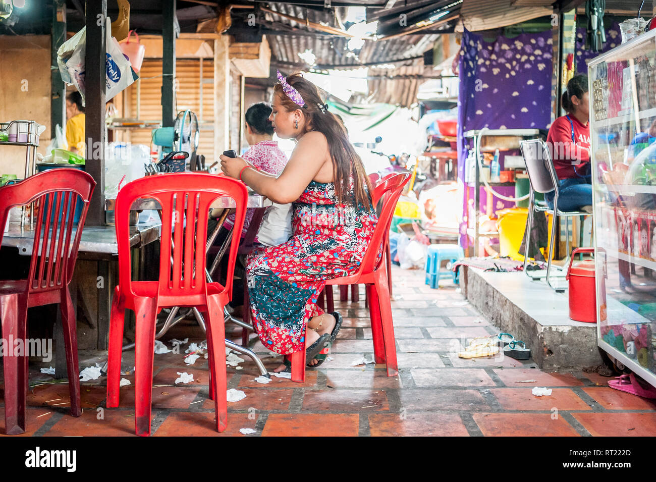 A young lady enjoys her lunch at a noodle stall in a busy indoor market in Phnom Penh Cambodia. Stock Photo