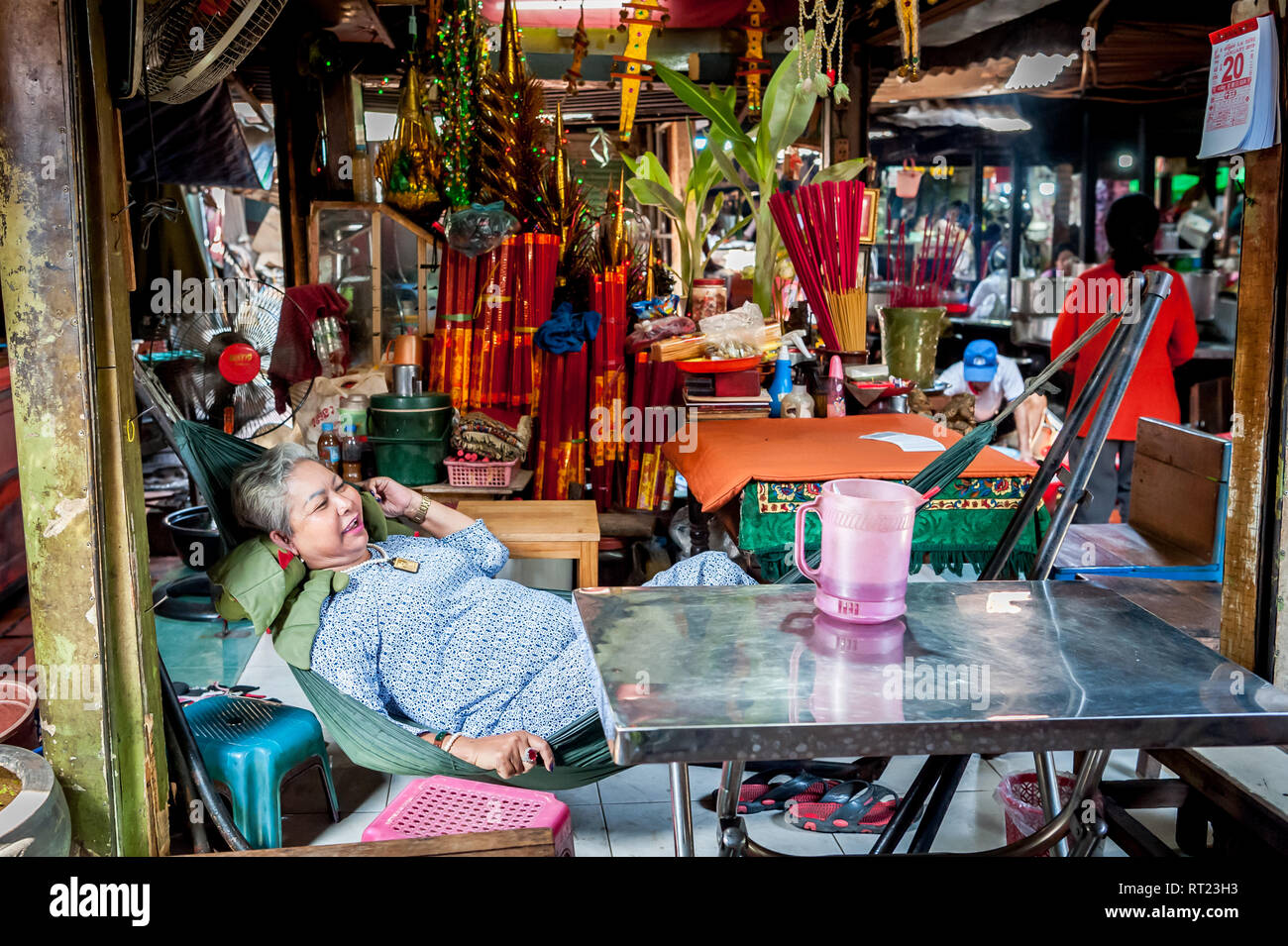 A Cambodian fortune teller relaxes at her stall waiting for a customer in a busy Phnom Penh indoor market. Phnom Penh Cambodia. Stock Photo