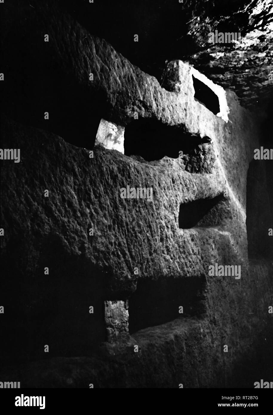 Erich Andres Italien - Catacombs witch niches in Rome, 1950s. Photo by Erich Andres Erich Andres - Italy, Italia, Rome, Roma, History, Historical, 1950s, Catacombs Italien - Grabnischen im weichen Tuffstein in den Katakomben von Rom in den 1950er Jahren Der Katakombenfriedhof, schon vor vielen Jahren geöffnet, und seines Inhalts beraubt. Andenkenräuber feierten hier schon im vorigen Jahrhundert Orgien. Inzwischen wurden diese Gänge vor dem weiteren Zugriff Fremder abgesichert. Fromme Mönche bewachen sie und lassen Fremde nur in geschlossenen Führungen passieren. 521/23 Stock Photo