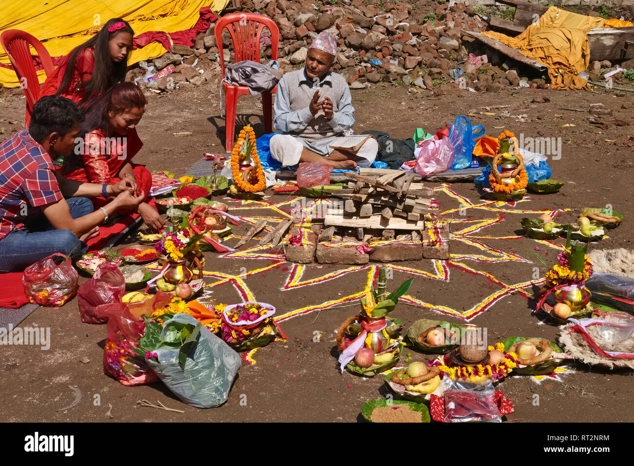 A Brahmin priest on the grounds of Budhanilakantha Temple in Kathmandu, Nepal, conducts a pooja (puja) or prayer ritual for a local family Stock Photo