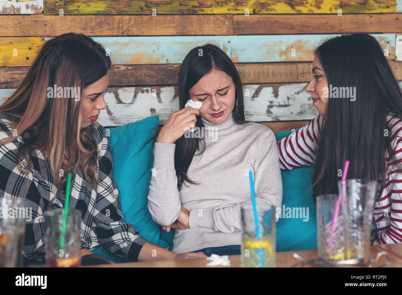 Friends supporting and consoling crying young woman Stock Photo