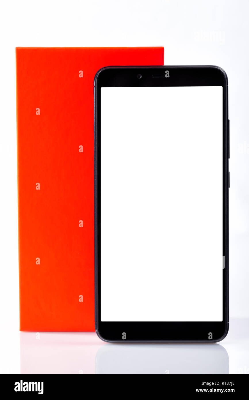A modern black smartphone with blank screen in front of its box isolated on white. Stock Photo