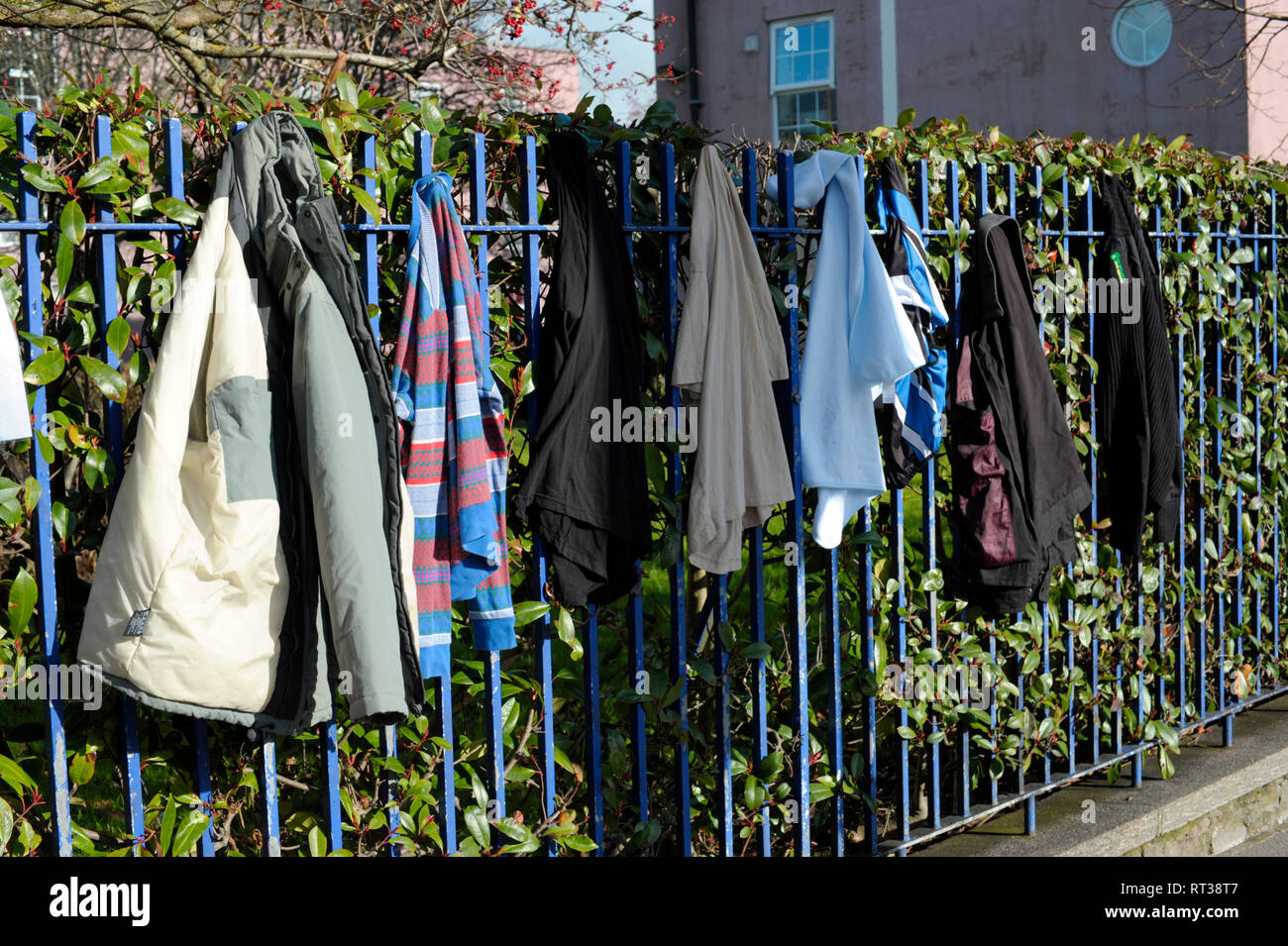 Display of clothing on fence near homeless charity shop in Plymouth Devon England UK Stock Photo