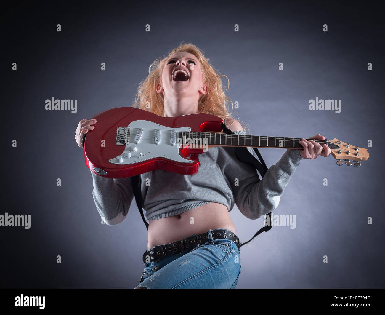 Attractive girl emotionally playing the electric guitar Stock Photo - Alamy